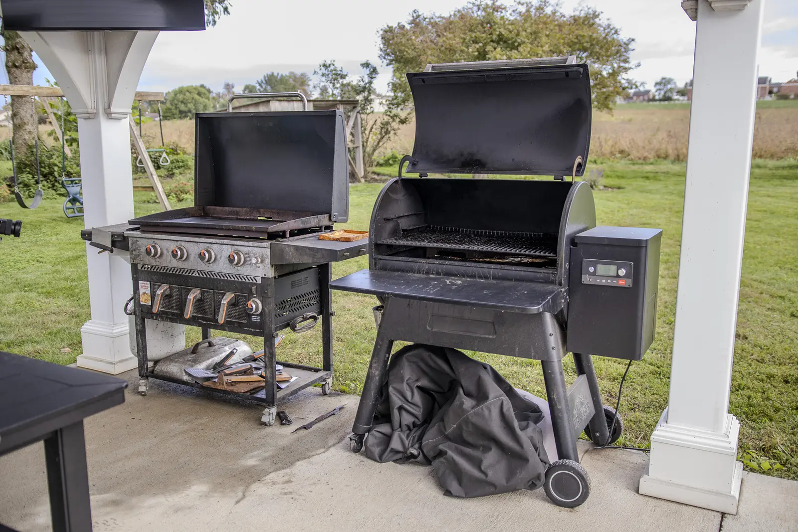 Two worn standalone grills on a patio