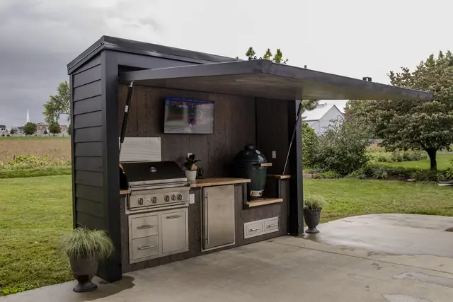 An open Flamehouse with the game on, grill, and ceramic egg